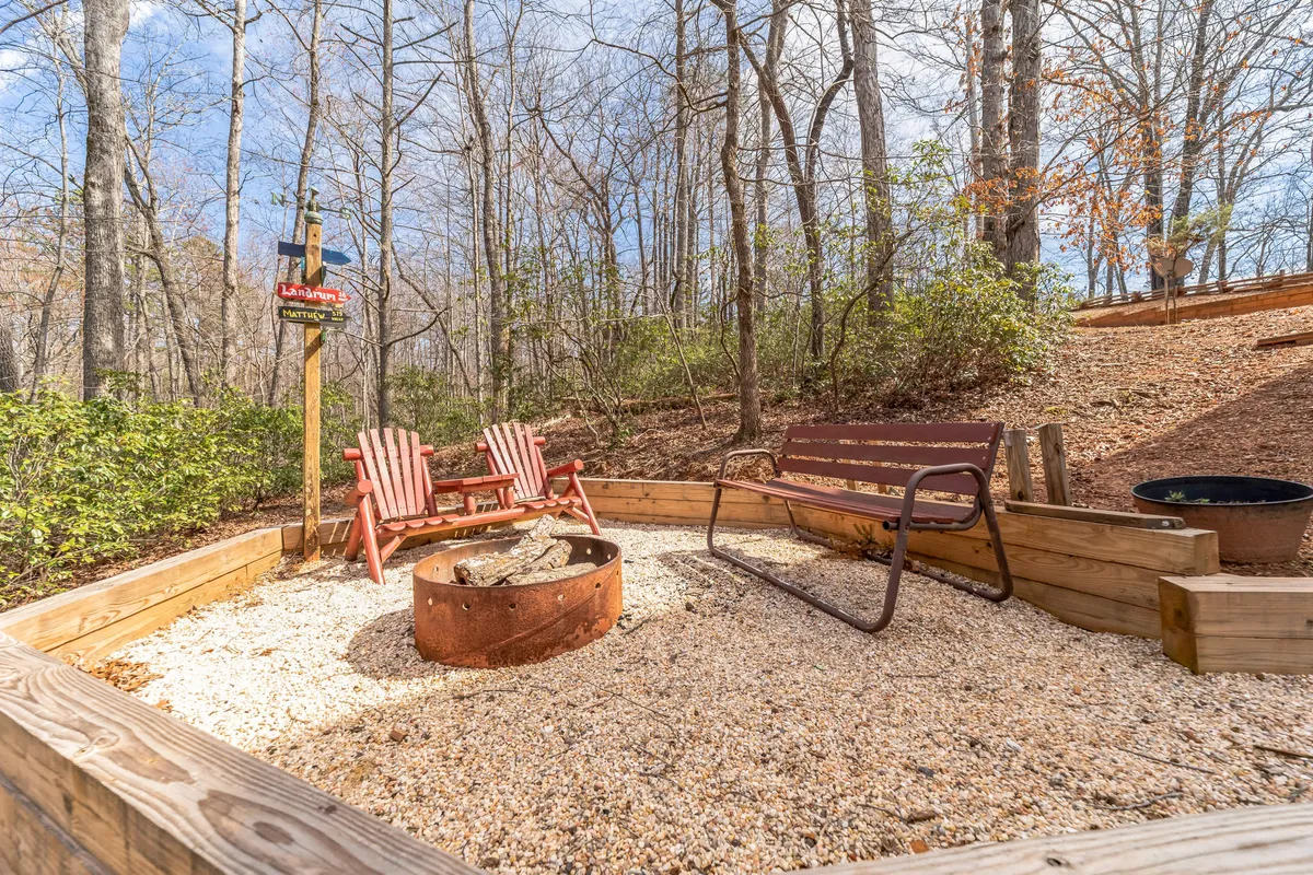 A vibrant outdoor seating area features red Adirondack chairs around a fire pit, with wooden benches and lush trees in the background. The space evokes feelings of togetherness and relaxation—ideal for unwinding after nature walks or sharing stories by the fire.