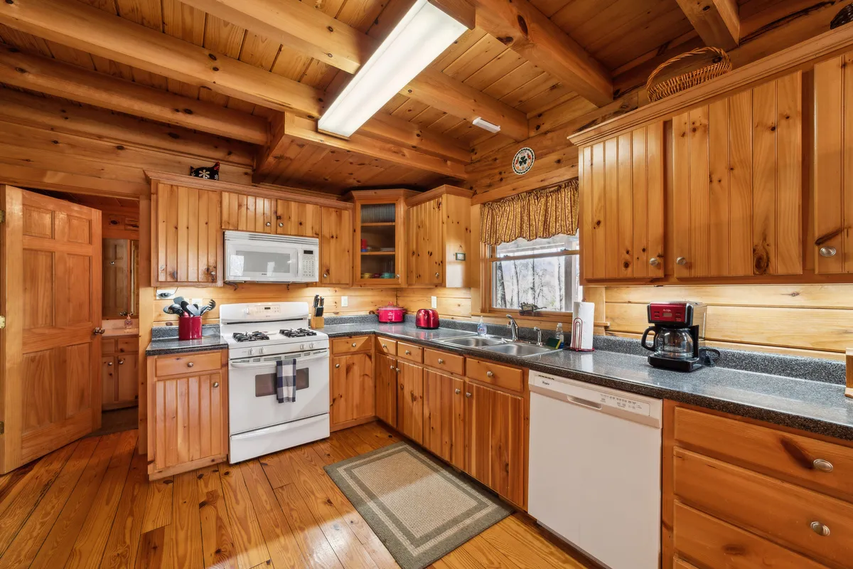 A well-equipped kitchen with wooden cabinets, ample counter space, and a charming window view. The kitchen is designed for cooking family meals, baking, and entertaining, adding a practical and homey aspect to the gathering spaces.