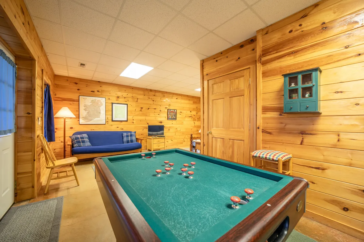 This image features a cozy game area with a pool table, sofa, lamp, and wooden walls. The warm lighting and comfortable seating invite guests to gather around for games and socializing, making it an ideal setting for evening tournaments or casual relaxation.